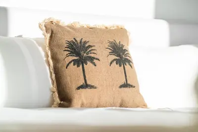 a pillow with palm trees on a white couch at GuestReady - The Ocean El Cid in Fajã da Ovelha