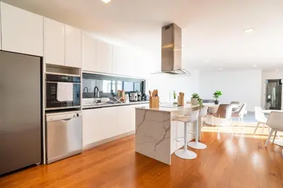 a kitchen with white cabinets and a kitchen island with stools at GuestReady - The Ocean El Cid in Fajã da Ovelha