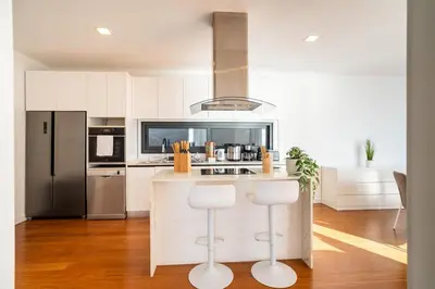 a kitchen with white cabinets and a counter with stools at GuestReady - The Ocean El Cid in Fajã da Ovelha