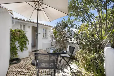 a patio with an umbrella and a table and chairs at Estúdio Agostinho in Luz