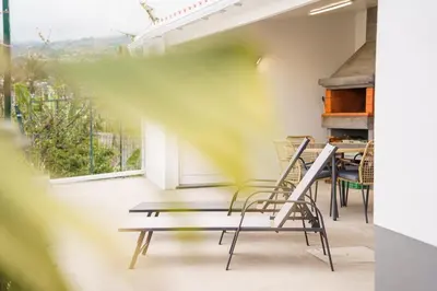 a room with a table and chairs on a balcony at GuestReady - Funchal Hideaway with BBQ in Funchal