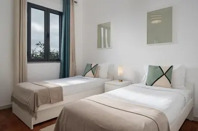 two beds in a white room with a window at Casa Maria Bela 2-Bedroom with Terrace in Calheta