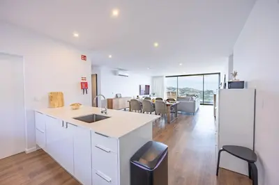 a kitchen with white cabinets and a table with chairs at Aurea Maris By YOUR KEY MADEIRA in Câmara de Lobos