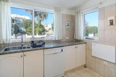 a kitchen with white cabinets and a sink and two windows at Casa da Areia, Three Bedroom Villa by the Beach in Luz