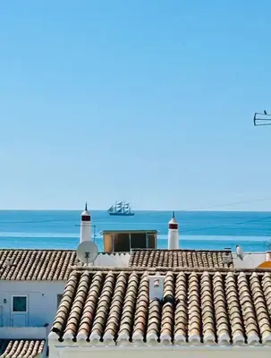 a view of the roofs of buildings with the ocean in the background at Casa da Areia, Three Bedroom Villa by the Beach in Luz