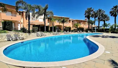 a swimming pool in a resort with chairs and palm trees at Quinta da Atalaia - Seaview Townhouse with pool in Lagos
