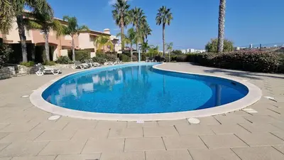 a large swimming pool in a courtyard with palm trees at Quinta da Atalaia - Seaview Townhouse with pool in Lagos