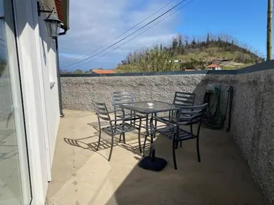 a table and chairs on a patio with a wall at My little home cottage in Porto Moniz