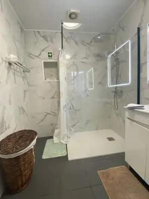 a white bathroom with a shower and a basket at My little home cottage in Porto Moniz