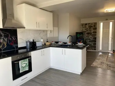 a kitchen with white cabinets and black counter tops at My little home cottage in Porto Moniz