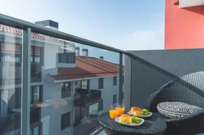 a table with plates of food and drinks on a balcony at Garajau Comfort Stay by Atlantic Holiday in Caniço