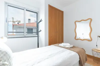 a white bedroom with a bed and a window at Garajau Comfort Stay by Atlantic Holiday in Caniço