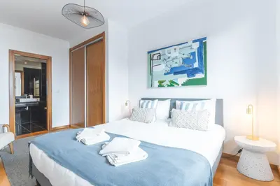 a bedroom with a large bed with a blue blanket at Garajau Comfort Stay by Atlantic Holiday in Caniço