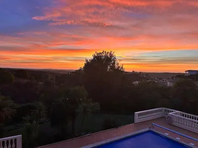 a sunset from the balcony of a house with a swimming pool at Luxury 4 Bedroom Algarve Villa with Private Pool in Budens