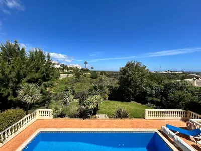 a swimming pool in front of a hill with trees at Luxury 4 Bedroom Algarve Villa with Private Pool in Budens