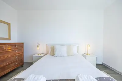 a white bedroom with a large bed and two night stands at Lux Mare Funchal by YOUR KEY MADEIRA in Funchal