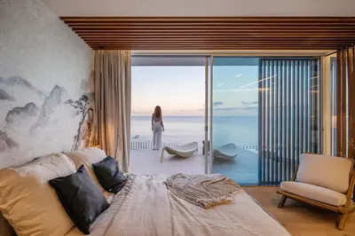 a bedroom with a bed and a woman standing on a balcony at Aurora Residence - Ultra Luxury Ocean Cliff Edge Retreat in Arco da Calheta