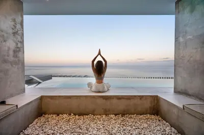 a woman sitting on the edge of a pool looking out at the ocean at Aurora Residence - Ultra Luxury Ocean Cliff Edge Retreat in Arco da Calheta
