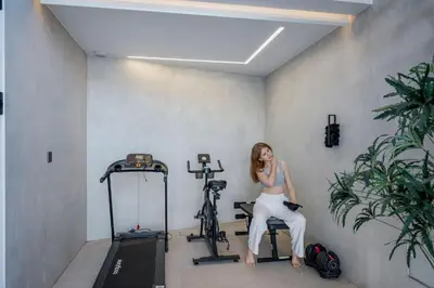 a woman sitting on a chair in a gym with a bike at Aurora Residence - Ultra Luxury Ocean Cliff Edge Retreat in Arco da Calheta