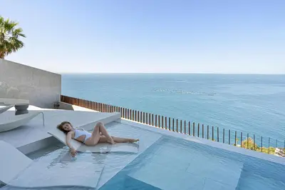 a woman laying in a swimming pool next to the ocean at Aurora Residence - Ultra Luxury Ocean Cliff Edge Retreat in Arco da Calheta