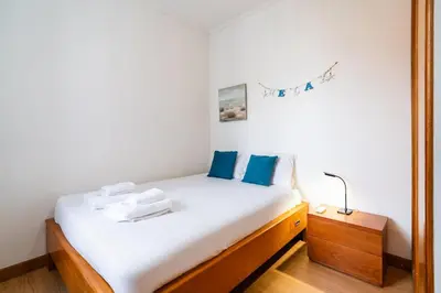 a bedroom with a bed with white sheets and blue pillows at GuestReady - Casa Martins in Machico