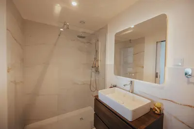 a bathroom with a sink and a shower and a mirror at Atlantic Residence Pool & Ocean View in Câmara de Lobos