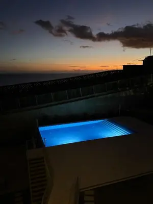 a lit up swimming pool on top of a building at sunset at Atlantic Residence Pool & Ocean View in Câmara de Lobos