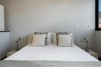 a bedroom with a white bed with two lamps at Stay Orange Modern Apartment in Funchal in Funchal