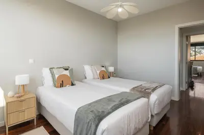 two beds in a white bedroom with a ceiling fan at Stay Orange Modern Apartment in Funchal in Funchal