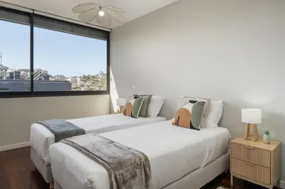 two beds in a bedroom with a large window at Stay Orange Modern Apartment in Funchal in Funchal