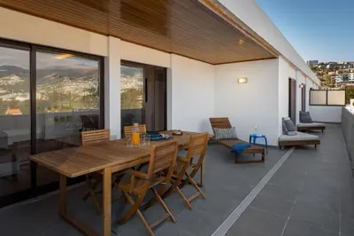 an outdoor patio with a wooden table and chairs at Monumental Alta Vista Panoramic View Balcony in Funchal