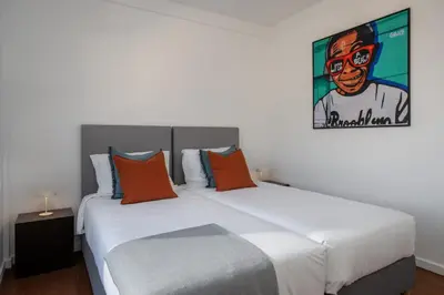 a bedroom with a large white bed with orange pillows at Monumental Alta Vista Panoramic View Balcony in Funchal