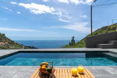 a pool with a basket of fruit and two glasses of orange juice at Arbor Villa: Nature Retreat in Campanário