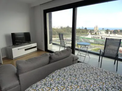 a living room with a couch and a television and a balcony at Pilot Ocean View in Funchal