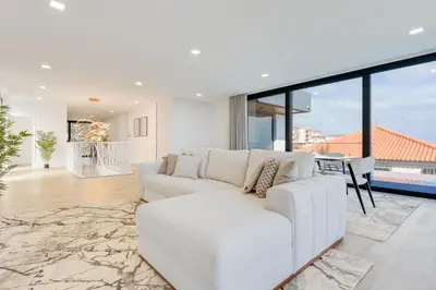 a living room with a white couch and large windows at Robbie's Place by Holiday Rental Madeira in Santa Cruz