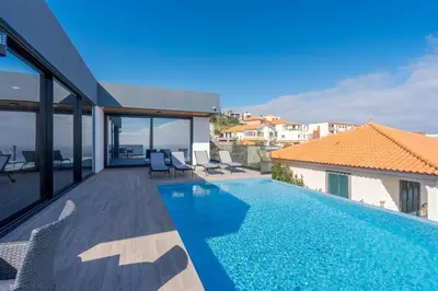 a table and chairs on a balcony with a swimming pool at Robbie's Place by Holiday Rental Madeira in Santa Cruz