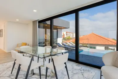 a dining room with a glass table and white chairs at Robbie's Place by Holiday Rental Madeira in Santa Cruz