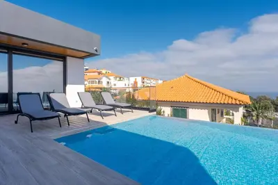 a house with a swimming pool and chairs on a deck at Robbie's Place by Holiday Rental Madeira in Santa Cruz