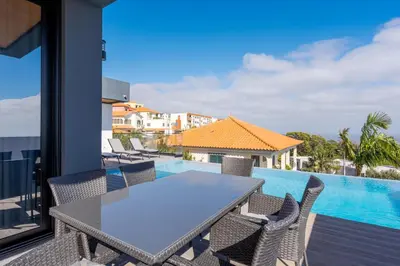 a swimming pool with chairs and a house at Robbie's Place by Holiday Rental Madeira in Santa Cruz