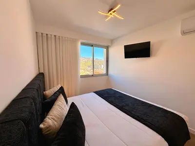 a bedroom with a bed and a tv and a window at Star Light Apartment in Câmara de Lobos