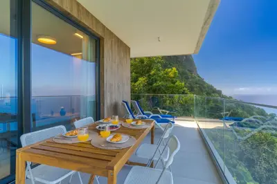 a dining room with a table and chairs on a balcony at Mar Yam Sea - Ocean View by Atlantic Holiday in Arco de São Jorge