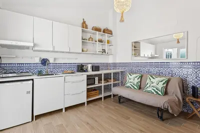 a kitchen with white cabinets and blue tiles on the wall at Pátio da Luz 1Bdr House by LovelyStay in Luz