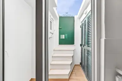 a hallway with white stairs and a green wall at Pátio da Luz 1Bdr House by LovelyStay in Luz