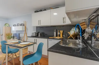 a kitchen with white cabinets and a table with blue chairs at Apartamentos Baptista by AnaLodges in Funchal