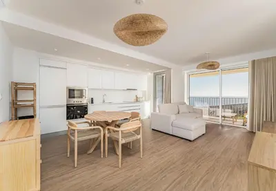 a kitchen and a living room with a table and chairs at Atlantic Pearl Pool & Ocean View One Bedroom Apartment in Câmara de Lobos