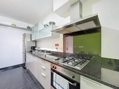 a kitchen with white cabinets and a stove top oven at Sea Garden in Caniço