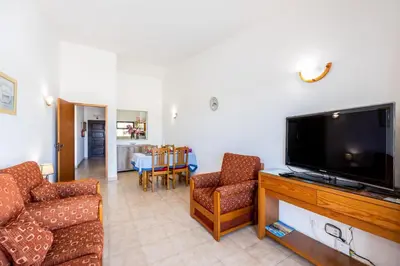 a living room with a flat screen tv and two chairs at Beach Front A in Luz