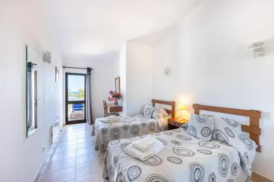 a bedroom with two beds and a hallway with a window at Beach Front A in Luz