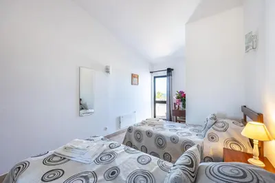 two beds in a white room with a window at Beach Front A in Luz