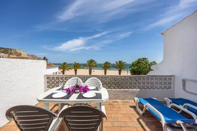 a table and chairs on a patio with a view of the ocean at Beach Front A in Luz